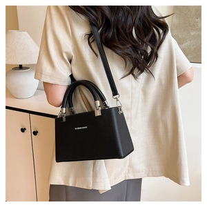 Side view of black lychee grain leather crossbody bag worn by a model in casual setting