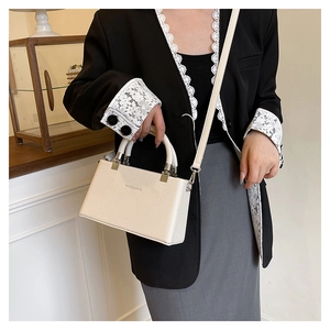 Detail of white lychee leather handbag with metal handle and thin shoulder strap