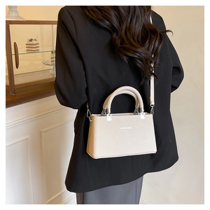 Detail of lychee pattern cream handbag showing silver hardware and fashion text logo