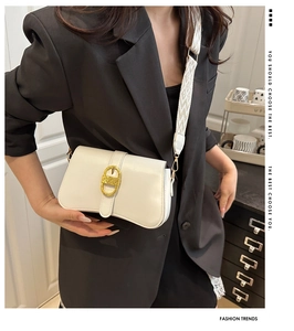 Close-up of white crossbody bag featuring gold buckle and geometric woven strap