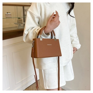 Brown lychee leather handbag detail with silver metal hardware and fashion text logo