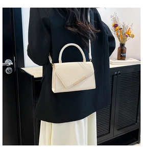 Detail of cream leather and straw crossbody bag with gold hardware on a shoulder strap