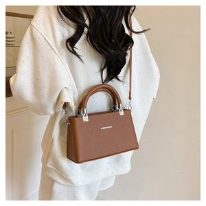 Close-up of brown litchi pattern leather handbag with silver hardware and shoulder strap