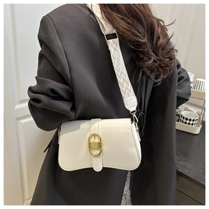 Detail of white leather shoulder bag with gold clasp and geometric woven strap on model