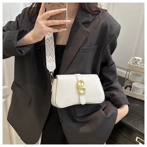 Close-up of white crossbody bag with gold oval buckle and geometric pattern wide strap