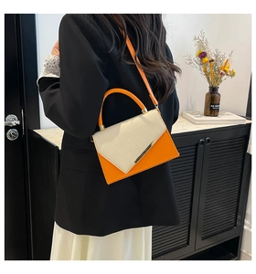 Detail of the orange and beige lizard textured crossbody bag shown on a model