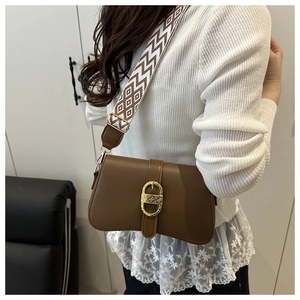 Detail of dark brown leather shoulder bag featuring a gold buckle and geometric wide strap