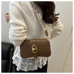 Detail of vintage brown leather bag with wide geometric strap and golden buckle
