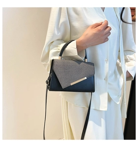 Detail of minimalist leather crossbody bag with fabric flap and golden metal buckle