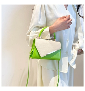 Detail of green leather handbag with straw texture flap and silver metal trim
