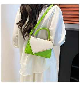 Detail of green leather and woven fabric crossbody bag with gold metal trim on model