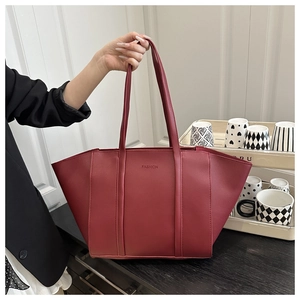 Detail of red leather tote bag with embossed Fashion logo and slim top handles