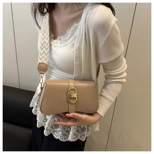 Detail of khaki shoulder bag featuring gold oval buckle and geometric fabric strap