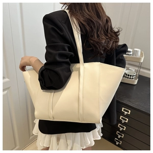 Model wearing a minimalist cream PU leather bucket bag with large capacity for daily commute