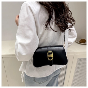 Close-up of stylish black faux leather shoulder bag with elegant gold buckle on model