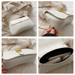 Detailed view of white half-moon bag featuring wide geometric strap and golden hardware