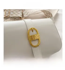 Detail of white leather shoulder bag with gold textured clasp and woven strap