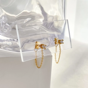 Detail of gold chain drop earrings with black zircon stud on a transparent display