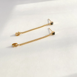 Macro shot of long tassel chain earrings with black zircon stones in gold finish