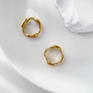 Detailed view of gold hoop earrings with bamboo texture on a white ceramic plate