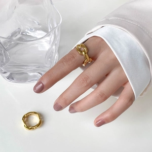 Detail shot of golden anchor link chain rings worn with a minimalist white suit