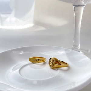 Detail of vintage gold angel relief and botanical engraved signet rings on a white plate