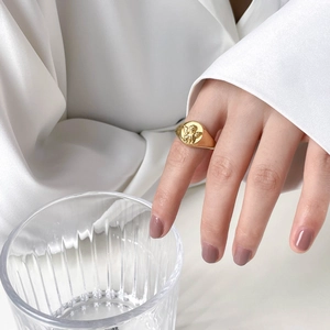 Close-up of vintage gold angel relief signet ring on finger with elegant aesthetic