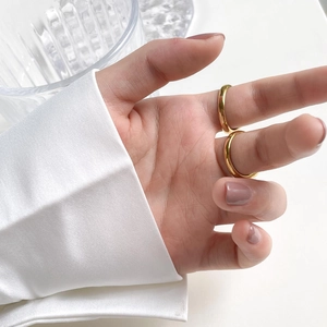 Detailed view of two thick polished gold-plated dome rings worn on a hand