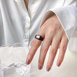 Detail of wide Mobius ring with brown enamel finish and rectangular white zircon stone
