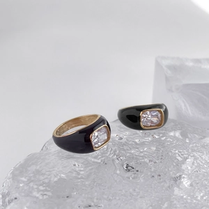 Detailed macro view of black enamel ring with gold trim and rectangular crystal stone