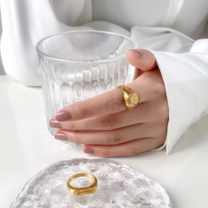 Detailed close-up of gold angel relief signet ring and textured band set on a model