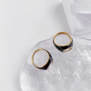 Detail of wide black enamel rings with rectangular zircon stones on textured glass tray