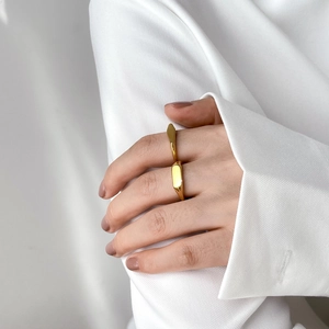 Anillo geométrico minimalista de acero de titanio dorado con facetas en la mano de mujer