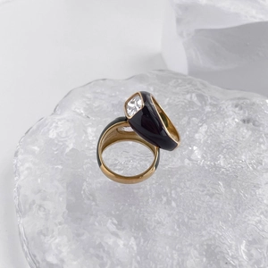 Detail of two black enamel gold rings set with sparkling white cubic zirconia crystals
