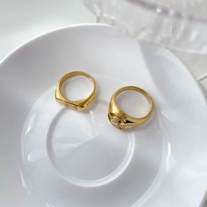 Detail of vintage gold signet rings with 3D angel relief on white ceramic plate