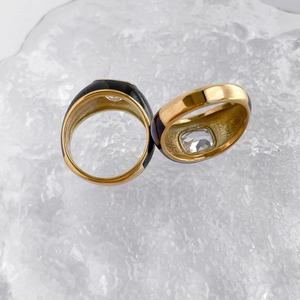 Detail of gold Mobius rings with black enamel and square zircon on ice crystal background