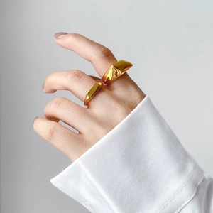Primer plano de anillos geométricos dorados gruesos en mano con puño de camisa blanca