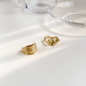 Détail de bagues dorées minimalistes avec texture ondulée sous une lumière élégante