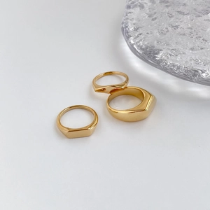 Detalle de tres anillos geométricos dorados minimalistas con superficies pulidas