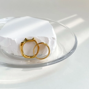 Détail d'une bague chat dorée et d'un anneau fin sur pierre et plateau en verre