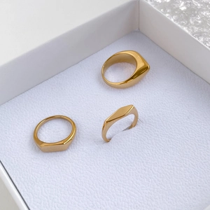 Juego de tres anillos geométricos dorados minimalistas en una elegante caja de joyas blanca