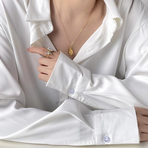 Détail d'une bague papillon dorée avec zircons portée sur un fond en tissu satiné blanc