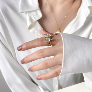 Détail de la bague papillon dorée avec zircons sur une chemise en soie blanche