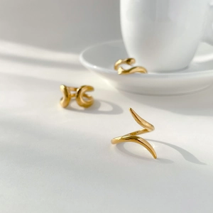 Detail shot of 18K gold plated minimalist spiral and abstract snake rings on white surface