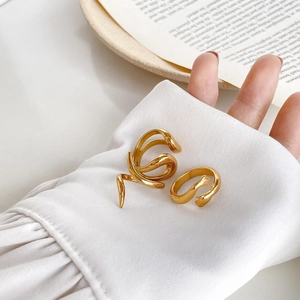 Detail of 18K gold-plated wrap ring and hands hugging ring on white shirt sleeve
