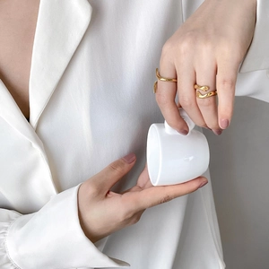 Minimalist 18K gold plated snake-shaped curve ring shown on a model holding a cup