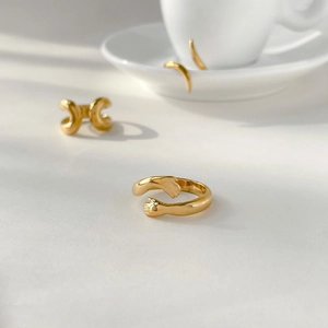 Macro detail of 18K gold plated hugging hands ring and wavy geometric band