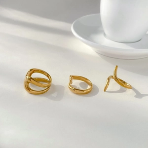 Close-up of minimalist 18K gold plated snake rings with organic fluid lines on white base