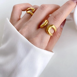 Macro view of two 18K gold plated irregular fluid rings on model hands with glossy finish