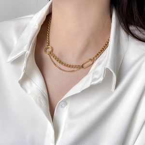 Gold layered chain necklace with chunky and thin links on a woman in white satin shirt